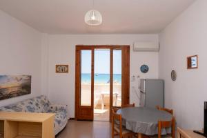 un salon avec une table et un réfrigérateur dans l'établissement Appartamento Coryna sul Mare, à San Vito Lo Capo