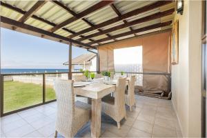 a dining room with a table and chairs and the ocean at Sea Breeze Beach House in Uvongo Beach