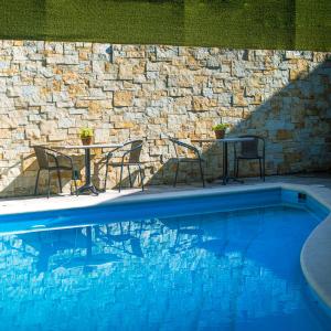 una piscina con sillas, mesas y una pared de piedra en Casa Bruna Luxury Lofts, en Tampico