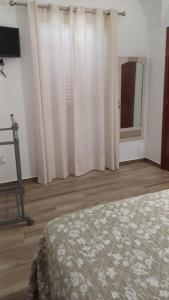 a bedroom with white curtains and a bed and a mirror at A Lapa in Mourão