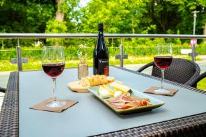 a table with two glasses of wine and a plate of food at Hotel am Park Bad Driburg in Bad Driburg
