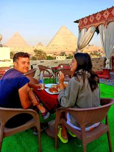 Um homem e uma mulher sentados à mesa a comer. em Arena pyramids view no Cairo