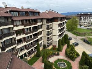 an apartment building with a garden in front of it at Alpine Lodge Bansko Apartments in Bansko