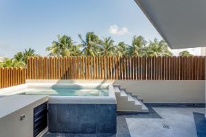 einen Pool mit einem Zaun und Palmen in der Unterkunft Aldea Thai by Mistik Vacation Rentals in Playa del Carmen