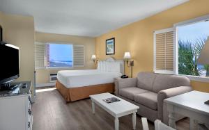 マートルビーチにあるBest Western Ocean Sands Beach Resortのベッドとソファ付きのホテルルーム