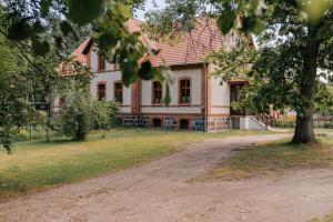 a large house with a tree in front of it at Leśniczówka Gołębia Góra in Unichowo