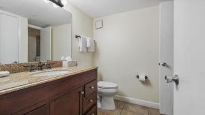 a bathroom with a sink and a toilet and a mirror at Cabana Club 206 Gulf Oceanfront, King Bed, private beach in Destin