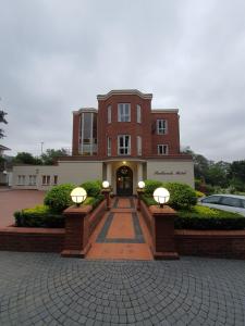 a large brick building with a walkway in front at Redlands Hotel in Pietermaritzburg