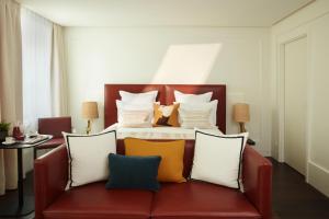 a bedroom with a bed with a red couch with pillows at Hotel La Villa Saint Germain Des Pr&eacute;s in Paris