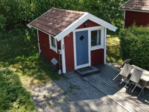 un cobertizo rojo con una puerta azul en una cubierta en Malmköpings Bad & Camping, en Malmköping