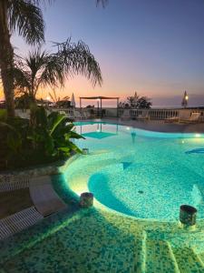 ein großer Pool mit Sonnenuntergang im Hintergrund in der Unterkunft Graceland rooms and suites in Capo Vaticano