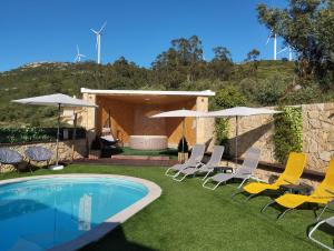 eine Gruppe von Stühlen und Sonnenschirmen neben einem Pool in der Unterkunft Da Serra guesthouse in Porto de Mós