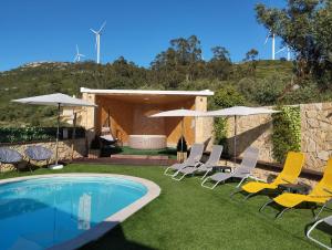 a group of chairs and umbrellas next to a pool at Da Serra guesthouse in Porto de Mós