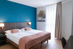 1 dormitorio con 1 cama grande y pared azul en Alp Art Hotel en Collombey