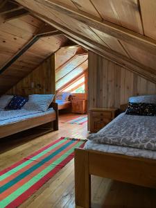 two beds in a room with wooden walls at Drinska Villa Cabin in Perućac