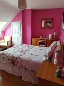 - une chambre aux murs roses avec un lit et une table dans l'établissement Bundoran Guesthouse, à Bundoran