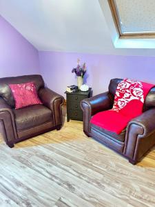 two leather chairs and a red pillow in a living room at Ballytigue House in Droíchead an Chláir