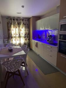 a kitchen with a table and blue lighting in it at NuriahBoutique Sacavém in Sacavém