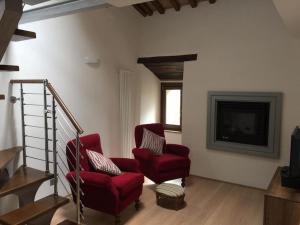 Una sala de estar con dos sillas rojas y un televisor. en Villa Marta, en Contignano