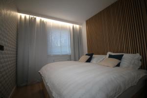 Apartament ARS Platinium Wisła في فيسلا: غرفة نوم مع سرير أبيض كبير مع نافذة