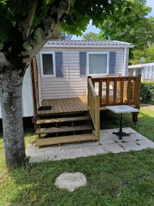 une cabane avec une terrasse à côté d'un arbre dans l'établissement MH 329 Camping Bois Dormant, à Saint-Jean-de-Monts
