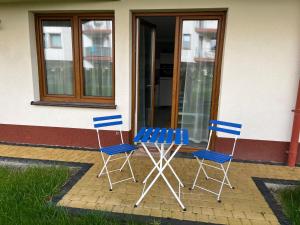 three blue chairs and a table in front of a building at Darba 2 in Darłowo