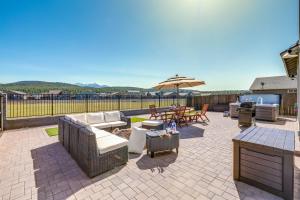 a patio with couches and tables and an umbrella at Spacious Bellemont Cabin with Jacuzzi and Mtn View! in Bellemont