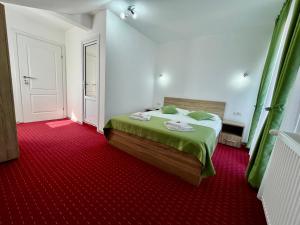 een slaapkamer met een bed met groene lakens en een rode loper bij Milea's Guesthouse in Bran