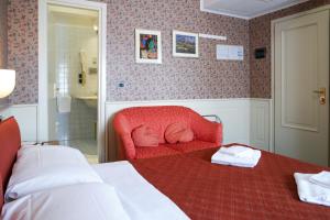 a bedroom with a bed and a red chair at Hotel alla giustizia in Mestre