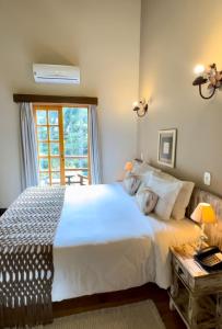 - une chambre avec un grand lit blanc et une fenêtre dans l'établissement Pousada Da Pedra, à Campos do Jordão