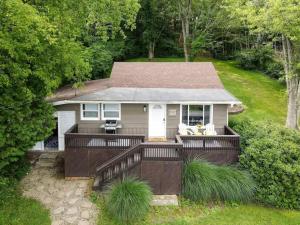 a small house with a large deck in the yard at Atwood Breeze-Tranquil Lake Escape in Sherrodsville