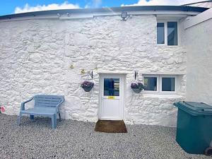 a white building with a blue bench in front of it at Bumblebee Cottage in Redruth