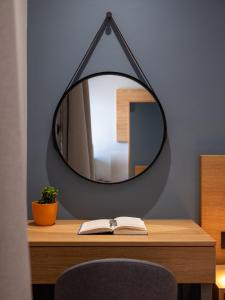 un espejo sentado en la parte superior de un escritorio con un libro en Athinaiko Hotel en Heraclión
