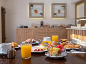 Athinaiko Hotel في مدينة هيراكيلون: طاولة مليئة بأطباق الطعام وعصير البرتقال