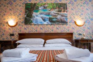 a bedroom with two beds and a waterfall painting on the wall at Hotel alla giustizia in Mestre