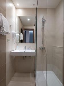 ein Bad mit einem Waschbecken und einer Dusche in der Unterkunft Athinaiko Hotel in Iraklio