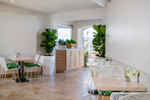 a dining room with tables and chairs and plants at Pacific Terrace Hotel in San Diego