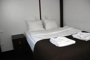a bed with white sheets and white towels on it at Rembrandt Aparthotel in Kraków