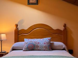 uma cama com uma cabeceira em madeira e uma almofada em Casa Rural El Salvijo em Monte
