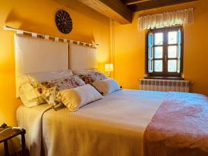 a bedroom with a large bed with yellow walls and a window at Casa Rural El Salvijo in Monte