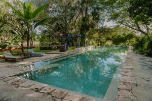 a swimming pool in a park with benches and trees at HACIENDA SANTO DOMINGO DE YUNKU in Yuncu