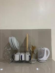 a shelf with cups and appliances on a kitchen counter at Llaguno City Inn in General Santos
