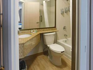 a bathroom with a toilet and a sink and a tub at Quality Inn Colchester - Burlington in Burlington