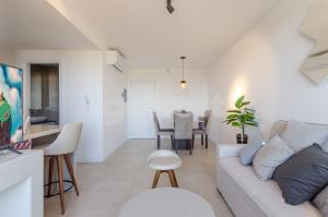 Delightful Apartment Near Shopping Del Sol في أسونسيون: غرفة معيشة مع أريكة بيضاء وطاولة
