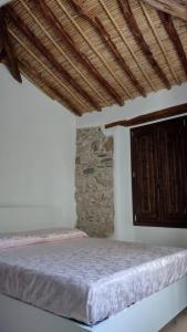 a bedroom with a bed and a wooden ceiling at Casa di Anna in Baunei