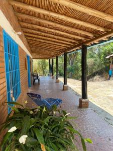 a patio with two blue chairs under a wooden pergola at Cabañas Villa Bayona in San Gil