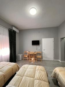 a bedroom with two beds and a table and a television at Zhuraj Apartments in Shkodër