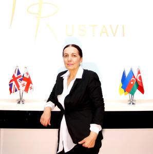 Eine Frau, die vor einem Tisch mit Fahnen steht. in der Unterkunft Hotel Rustavi in Rustawi