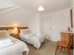1 dormitorio con 2 camas y silla de madera en Prospect Lodge, en Portinscale