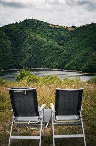 dos sillas sentadas frente a un cuerpo de agua en Vila Helena -Apartman 3, en Nova Varoš